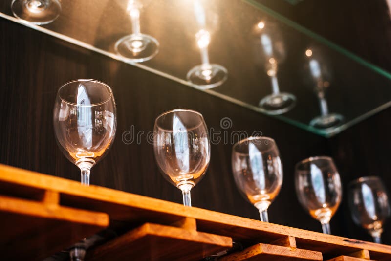 Drinking wine glasses shelf in restaurant with lighting showcase background. Many clean containers in restaurant or night pub and bar. Interior decoration and beverage party concept