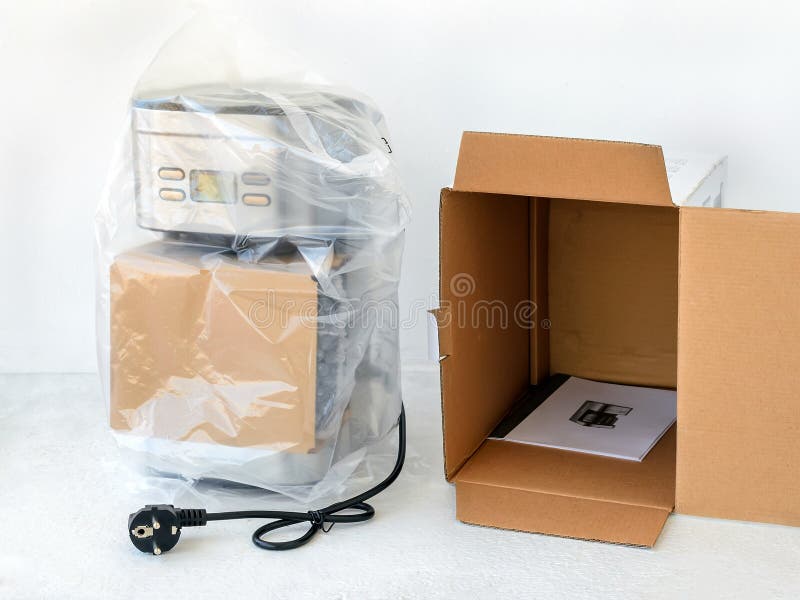 Drip-type coffee maker is in cellophane and near its cardboard box with instruction manual. Unpacking a new coffee machine. royalty free stock images Drip-type coffee maker is in cellophane and near its cardboard box with instruction manual. Unpacking a new coffee machine. royalty free stock images