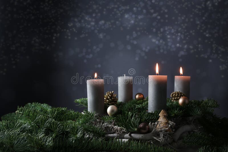 Dritte Einleitung mit drei brennenden Kerzen auf Tannenzweigen mit Weihnachtsdekoration gegen einen dunkelgrauen Hintergrundkopien stockfotos