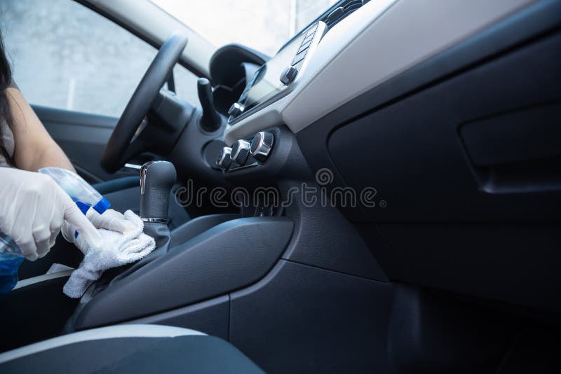 Driver Disinfecting the Interior of a Car with Spray and Rag for Covid