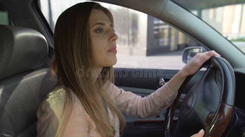 Driver femminile attento che lascia stazione di servizio e che guarda in retrovisori