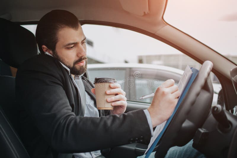 The driver going on the road, speaking on the phone, working with documents at the same time. Businessman doing multiple tasks. Multitasking business person