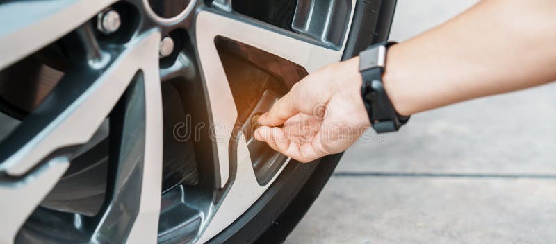 Driver hand inflating tires of vehicle, removing tire valve nitrogen cap for checking air pressure and filling air on car wheel at. Gas station. self service