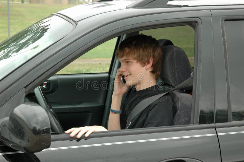 Driver teenager con un telefono delle cellule fotografia stock libera da diritti Driver teenager con un telefono delle cellule fotografia stock libera da diritti