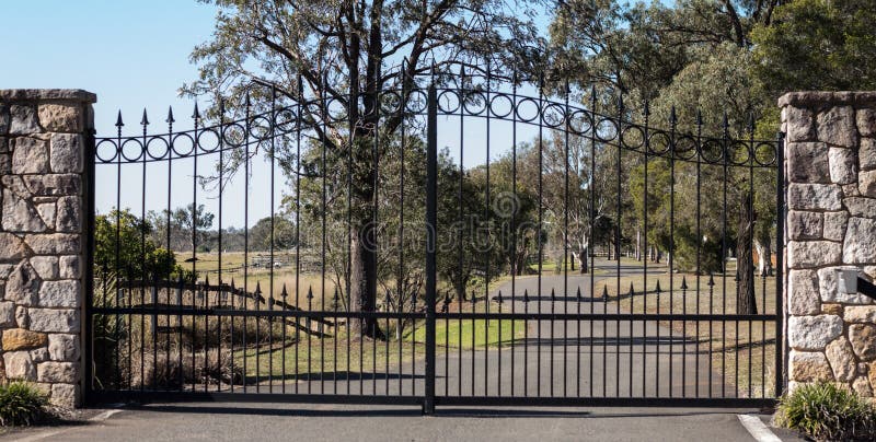 Driveway μετάλλων πύλες εισόδων ιδιοκτησίας που τίθενται αγροτικές στο φράκτη τούβλου ψαμμίτη με τα δέντρα γόμμας ευκαλύπτων στο στοκ εικόνα