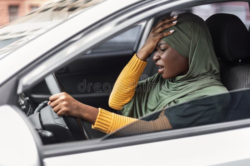 Driving Anxiety. Stressed Black Muslim Lady In Hijab Having Car Accident, African Islamic Lady Suffering Strong Headache While Drives Vehicle, Touching Head, Feeling Angry, Side View Shot