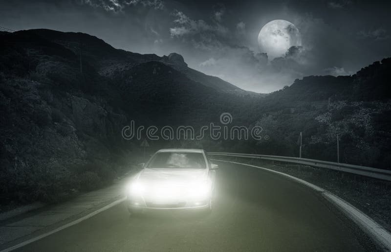 Driving on an asphalt road towards the headlights of car at night