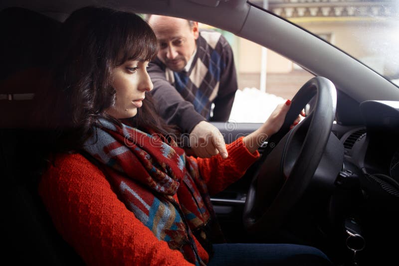 Driving instructor showing female student how to drive a car