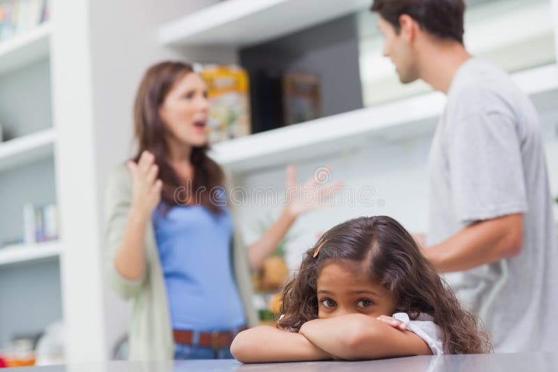 Droevig meisje die aan haar ouders het debatteren luisteren stock foto Droevig meisje die aan haar ouders het debatteren luisteren stock foto