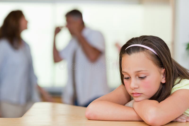 Droevig meisje met haar vechtende ouders achter haar royalty-vrije stock afbeelding Droevig meisje met haar vechtende ouders achter haar royalty-vrije stock afbeelding
