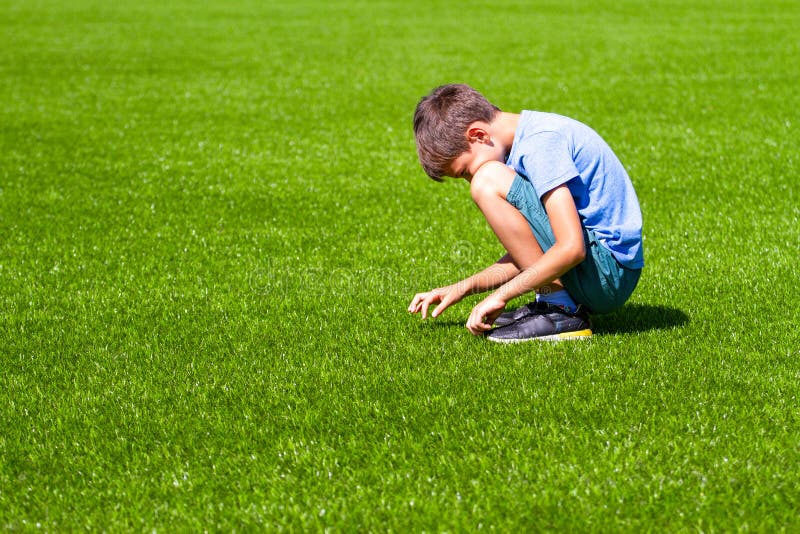 Droevige alleen jongenszitting op het gras in openlucht royalty-vrije stock afbeeldingen Droevige alleen jongenszitting op het gras in openlucht royalty-vrije stock afbeeldingen
