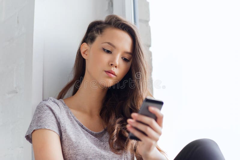 Droevige mooie tiener met smartphone het texting stock foto's Droevige mooie tiener met smartphone het texting stock foto's