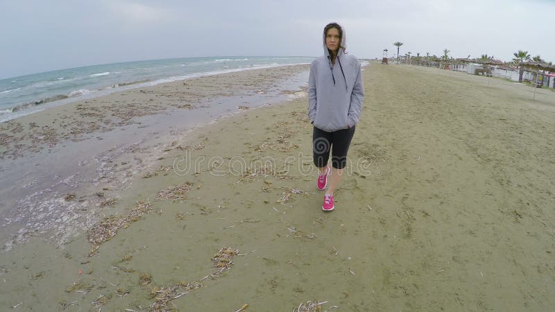 Droevige vrouw in sportkleding die langs strand lopen en over vriend denken