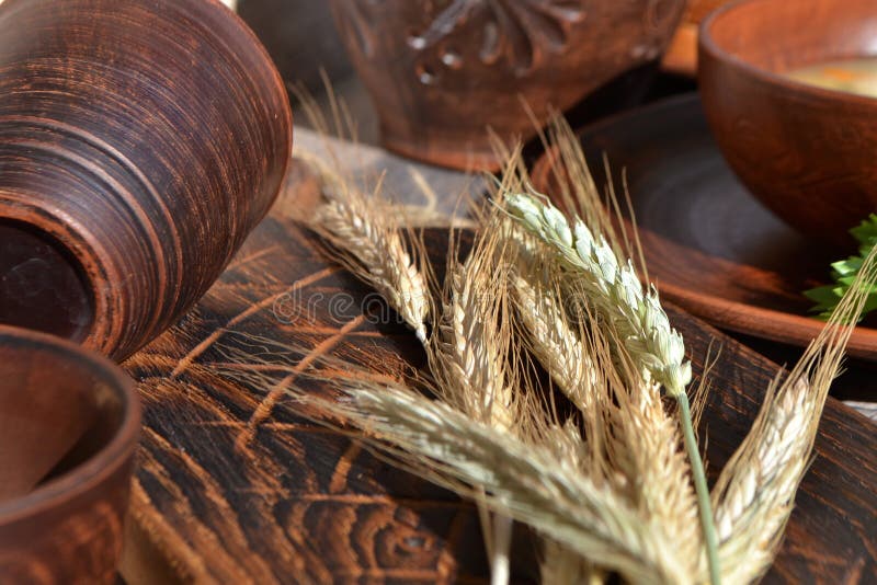 Droge broodaren met ceramische kommen en mok op een bruine houten lijst De herfstoogst van brood stock foto Droge broodaren met ceramische kommen en mok op een bruine houten lijst De herfstoogst van brood stock foto