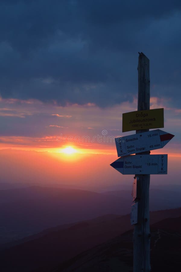 Drogowskaz turystyczny na górskiej drodze o zachodzie słońca