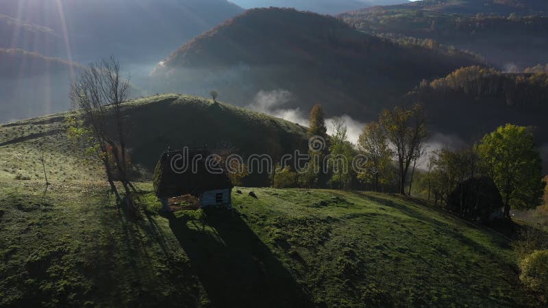 Drohblick auf eine Berghütte. Landschaftliche Nebellandschaft im Herbst mit verlassenen Häusern mit Strohdach