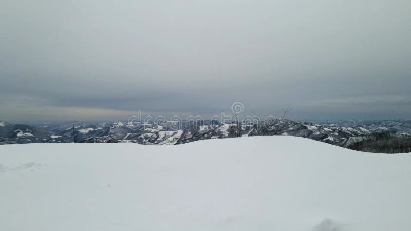 Drone flying over a snow-covered highland to reveal an expansive snowy mountain landscape stock footage