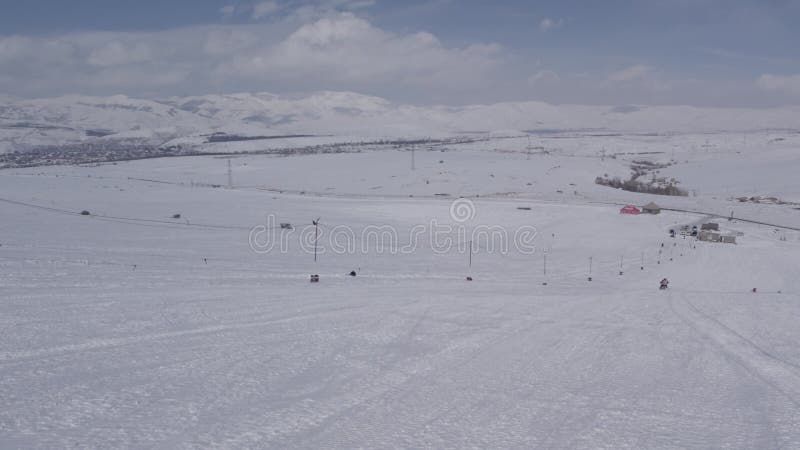 Drone footage of a snowmobile driving down on a snowy mountain stock video footage