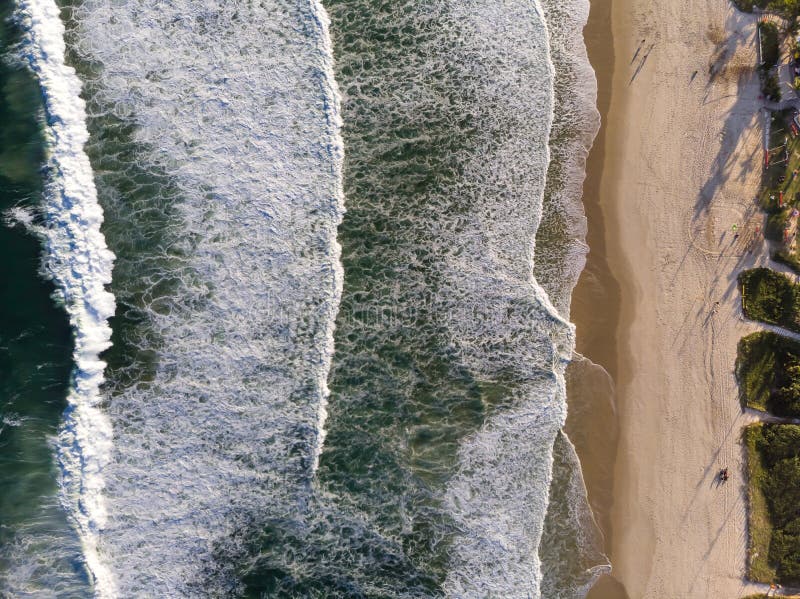Top view Drone photo of beach in Barra da Tijuca, Rio de Janeiro, Brazil. Waves crashing with whitewash, the golden sand and the b