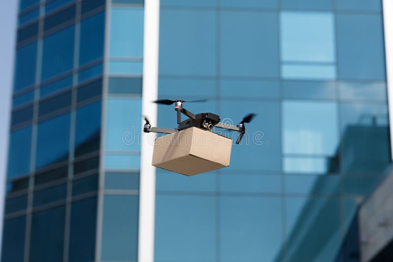 Drone Quadcopter Carrying a Package through the City Stock Photo