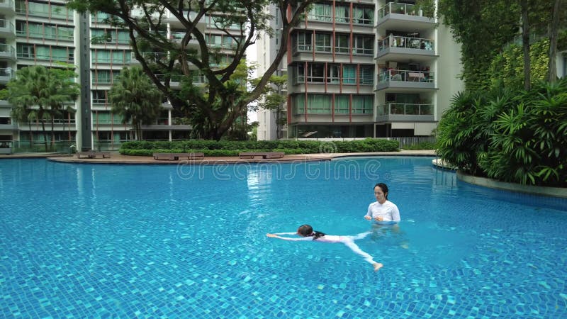 Drone shot of child swimming away from other in a beautiful swimming pool in the condominium, singapore