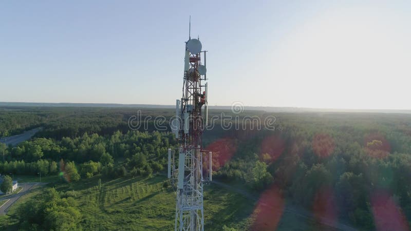 Drone view at telecommunication tower, worker servicing cellular antenna