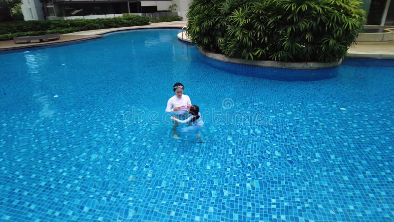 drone zoom in on mother and child playing in a beautiful swimming pool in the condominium, Singapore