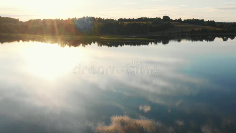 Drone πετούν πάνω από ριγμένα νερά λίμνης αντανακλώντας τις στάσεις του ουρανού πάνω σε ένα εκπληκτικό, ήρεμο πράσινο καλοκαίρι ηλ φιλμ μικρού μήκους