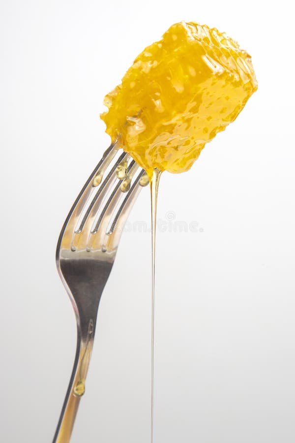 Drops of Fresh Honey Drip from Wax Honey on a Table Fork. Vitamin