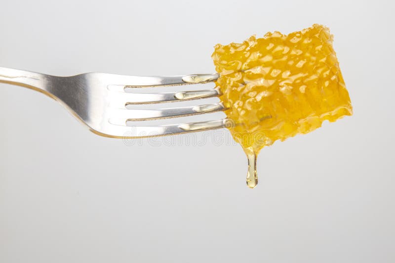 Drops of Fresh Honey Drip from Wax Honey on a Table Fork. Vitamin
