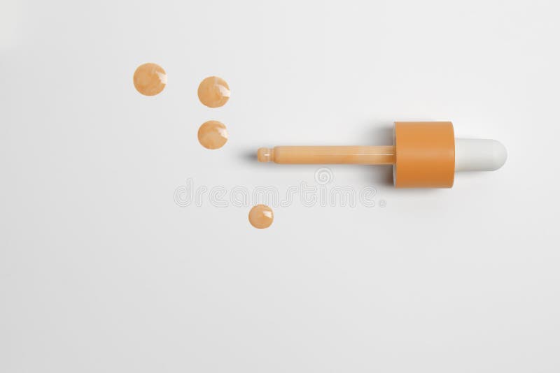 Drops of Liquid Skin Tint Serum Foundation Applied from Dropper on White Background. Stock