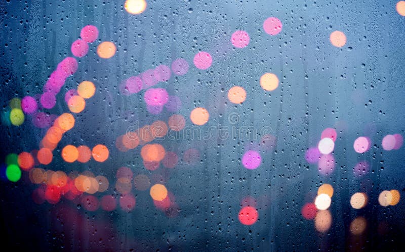 Drops of rain on glass with defocused lights. Urban abstract background