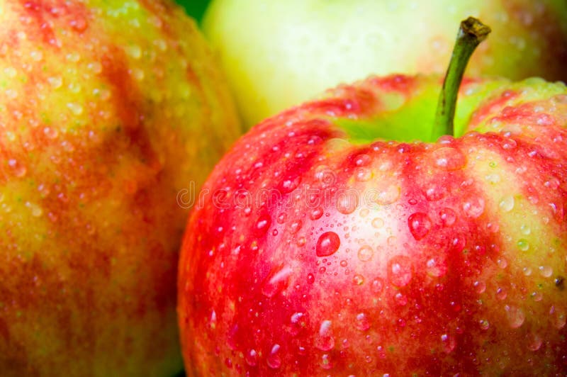 Drops of water on an apple closeup on a background of apples