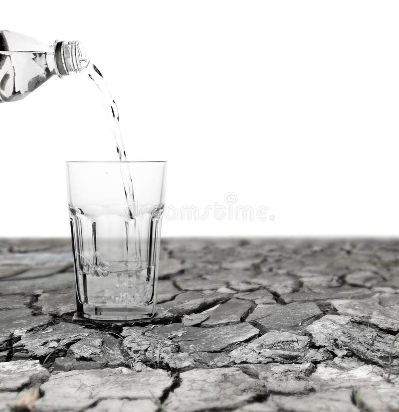 Water being poured out from a mineral water bottle into a crystal glass sitting on a drought stricken dry cracking mud surface with blank space for text. Water being poured out from a mineral water bottle into a crystal glass sitting on a drought stricken dry cracking mud surface with blank space for text.