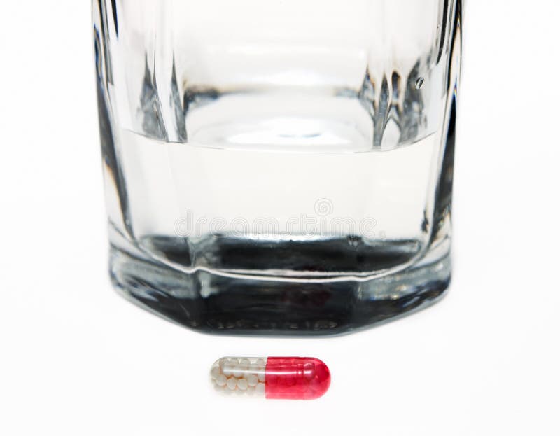 Drug pill in front of glass of water