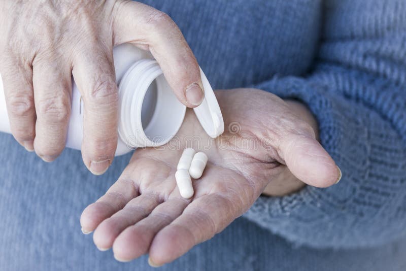 Drug pills on old woman`s hand