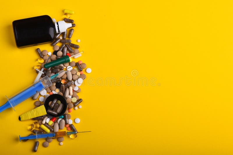 Drugs with syrup bottle, syringes, pipette and spoon. Set of colorful pills scattered on yellow background, copy space. Medicine and treatment concept. Frame made of pills and capsules put in line