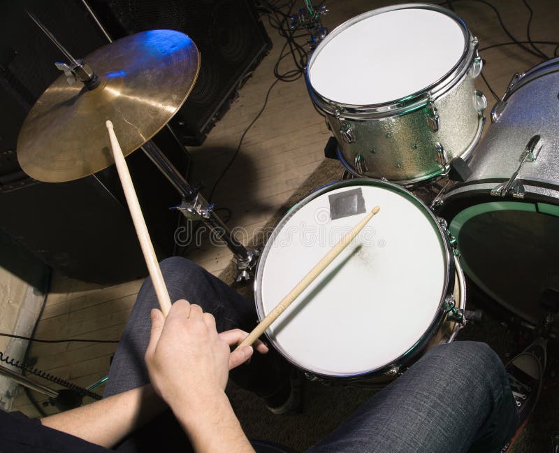 Above view of drummer's hands holding drumsticks playing on drumset. Above view of drummer's hands holding drumsticks playing on drumset.