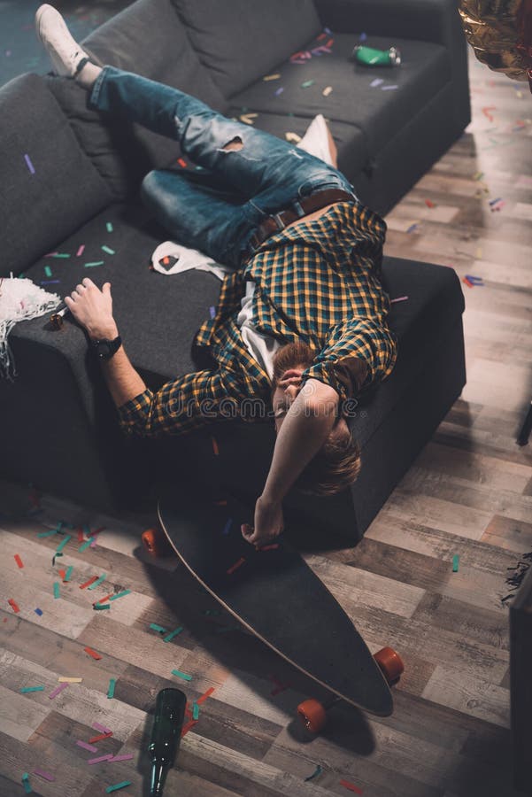 Drunk bearded young man sleeping on couch in messy room stock photography Drunk bearded young man sleeping on couch in messy room stock photography