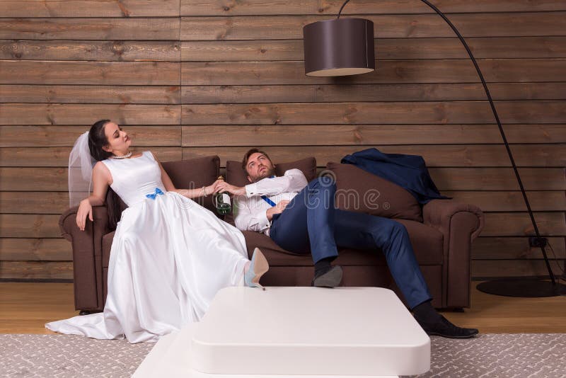 Drunk bride and groom relax on couch after wedding