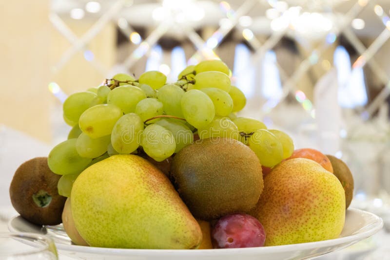 Druvor päron, kiwi, plommon, äpple i en platta Uppläggningsfat för efterrättfrukt Tabellinbrott en restaurang eller ett kafé royaltyfria foton Druvor päron, kiwi, plommon, äpple i en platta Uppläggningsfat för efterrättfrukt Tabellinbrott en restaurang eller ett kafé royaltyfria foton