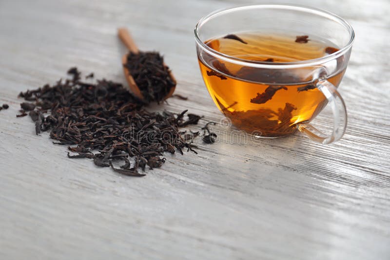 Dry Black Tea Leaves and Cup of Aromatic Beverage on Table Stock Image