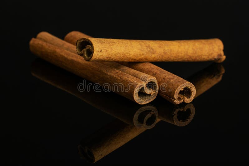 Dry brown cinnamon isolated on black glass