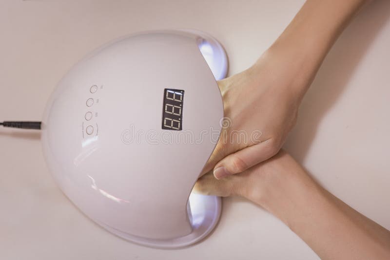 Drying Nails in the Ultraviolet Lamp. Salon Manicure Stock Photo