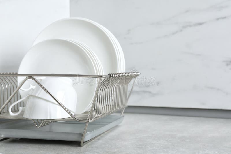 Drying Rack with Clean Dishes and Cups on Table in Kitchen. Stock Photo
