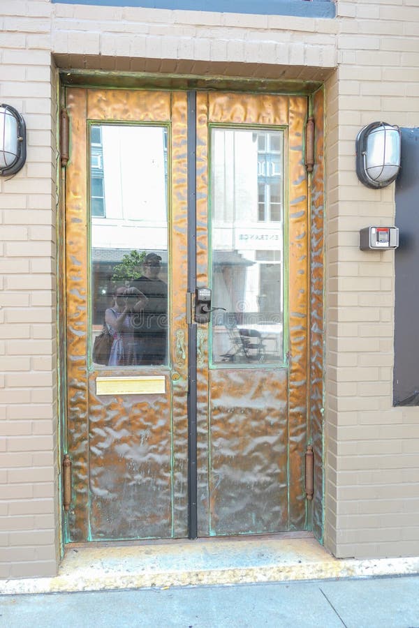 Hammered metal double doors with windows set in a painted brick building. Hammered metal double doors with windows set in a painted brick building.