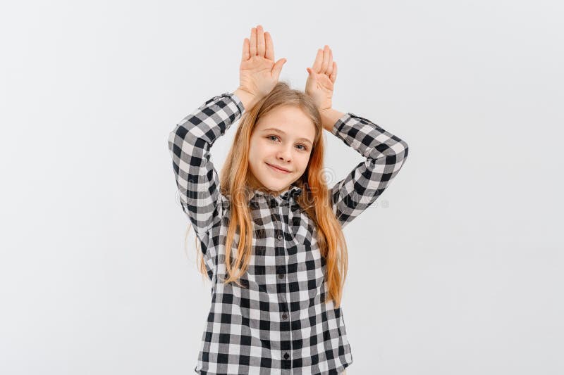 Drôle adolescente debout sur fond blanc faire des oreilles lapin gestes avec les mains palmiers avoir l'air heureux et heureux. la photo stock