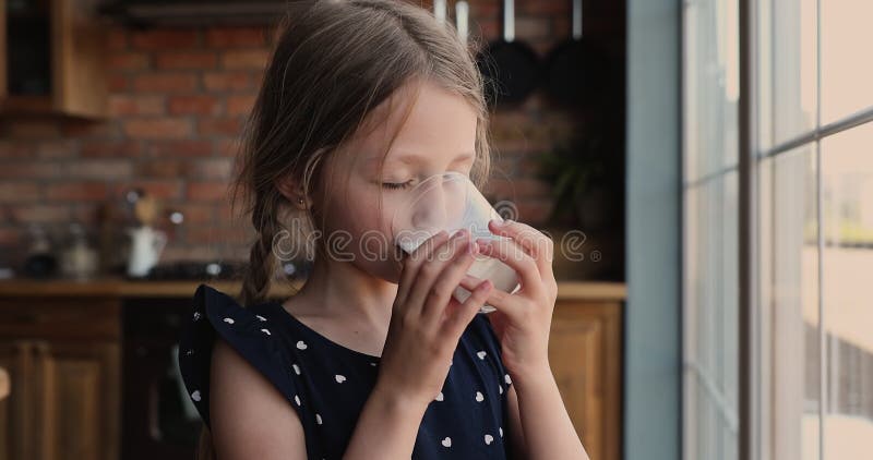 Drôle mignonne petite fille boire un verre de lait ou de yaourt.