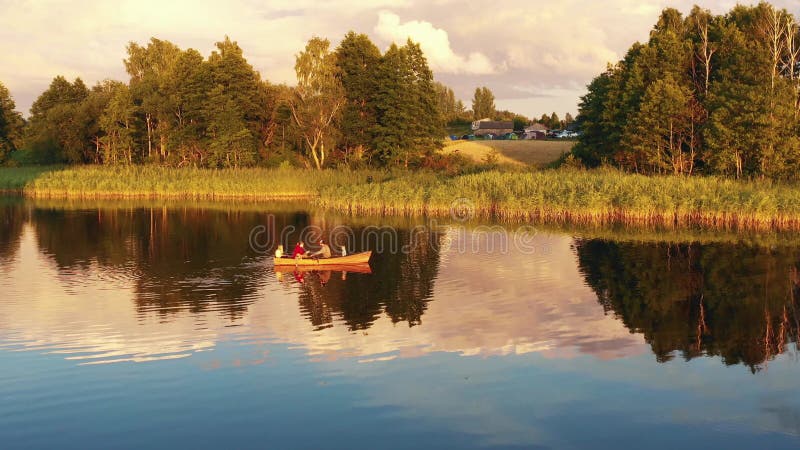 Drönare som flyger mot en lycklig familj med barn som åker med en båt tillsammans på en otrolig sommarsoluppgång.