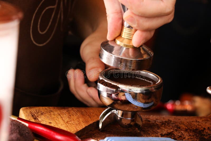 Drücken des gemahlenen Kaffees mit Besetzer stockfotografie Drücken des gemahlenen Kaffees mit Besetzer stockfotografie